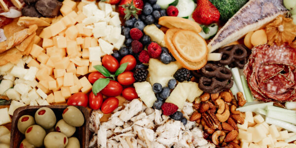 platter of food including cheese, olives, tomatoes, and assortments of fruits, meat, and nuts
